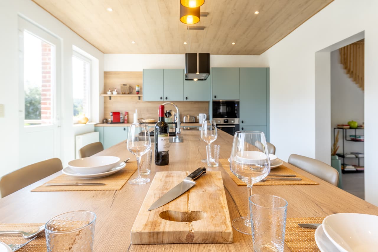 Gedekte tafel in de lengte, tegenover de zeegroene kasten
