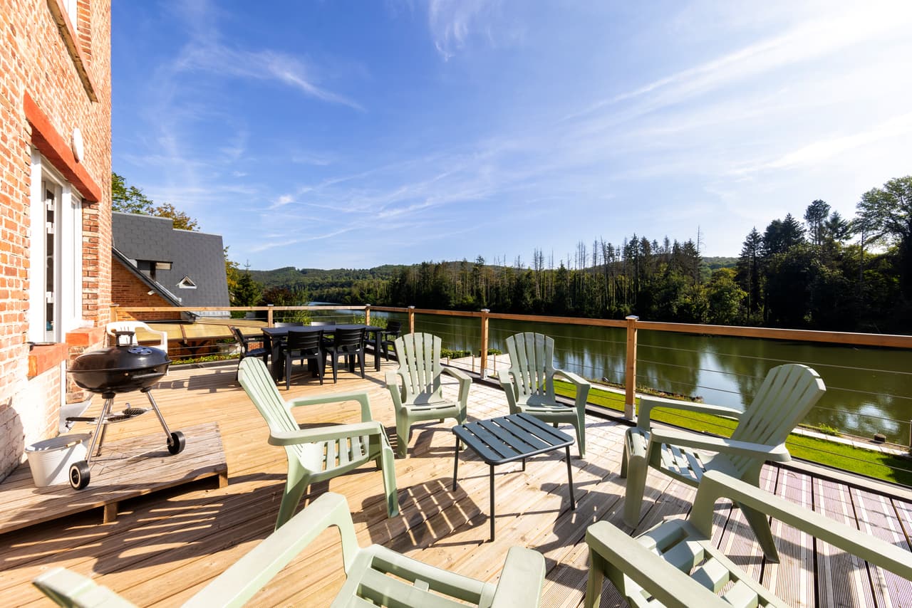 Houten terras met Adirondackstoelen, barbecue en zicht op de Maas
